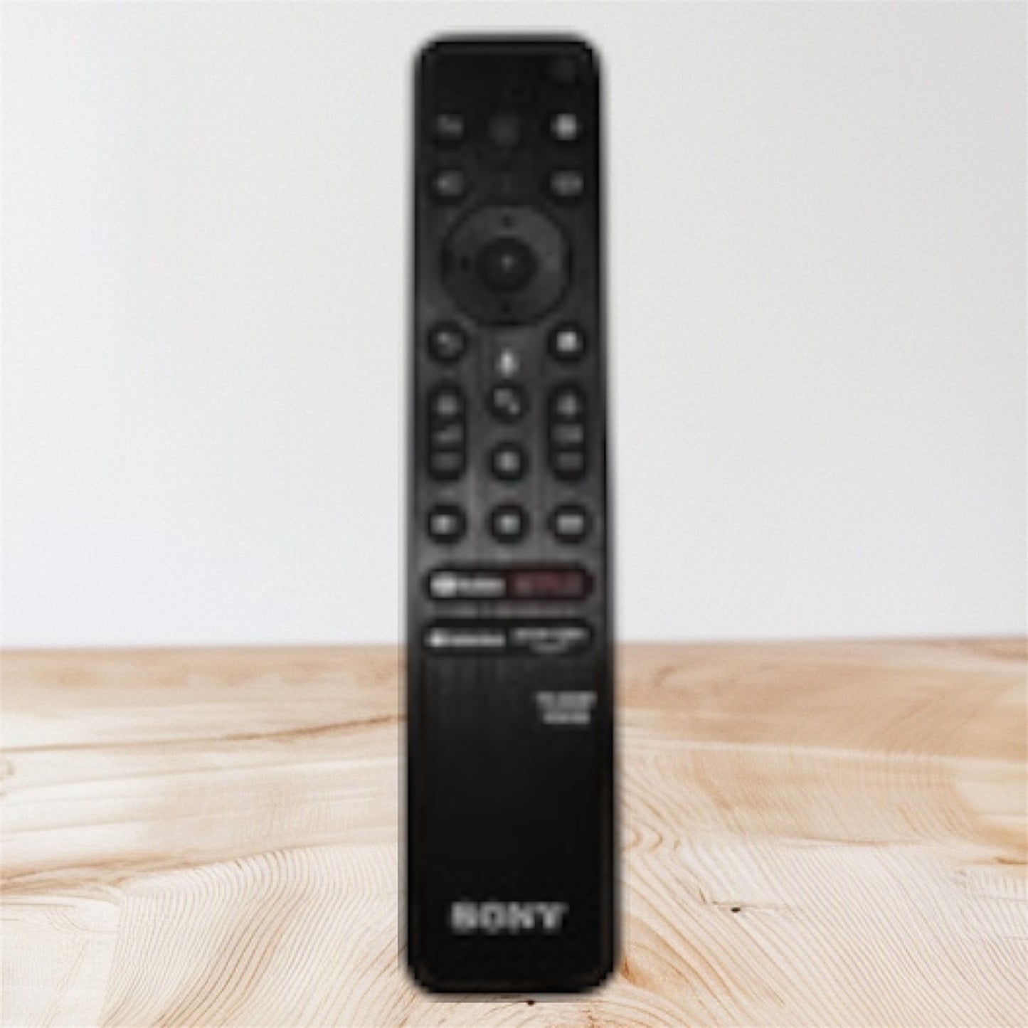 Black Sony remote control on a wooden surface with a light gray background