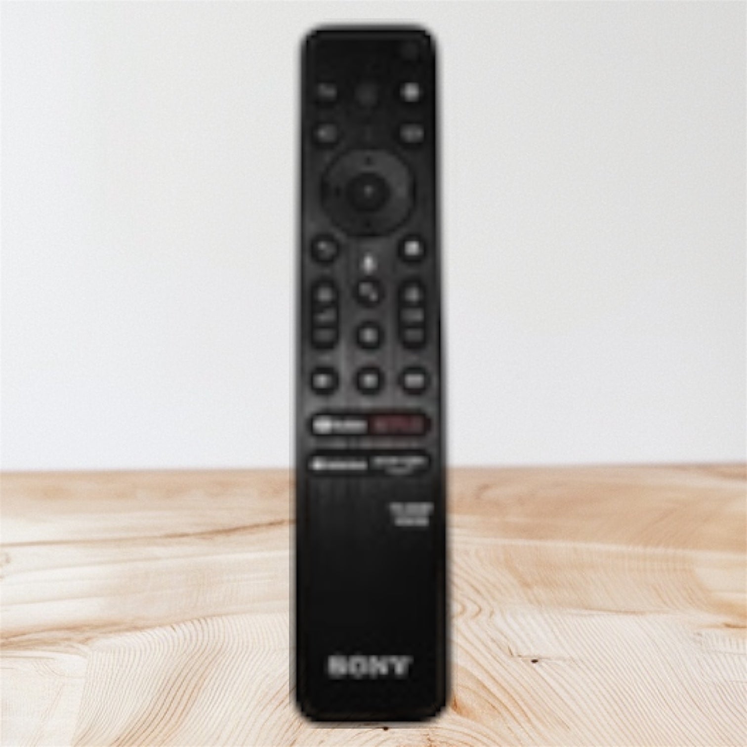 Black Sony remote control on a wooden surface with a light gray background