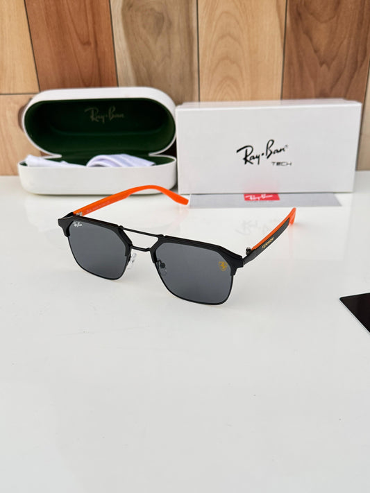 Ray-Ban sunglasses with black frame and orange arm on a white surface, with Ray-Ban packaging in the background.