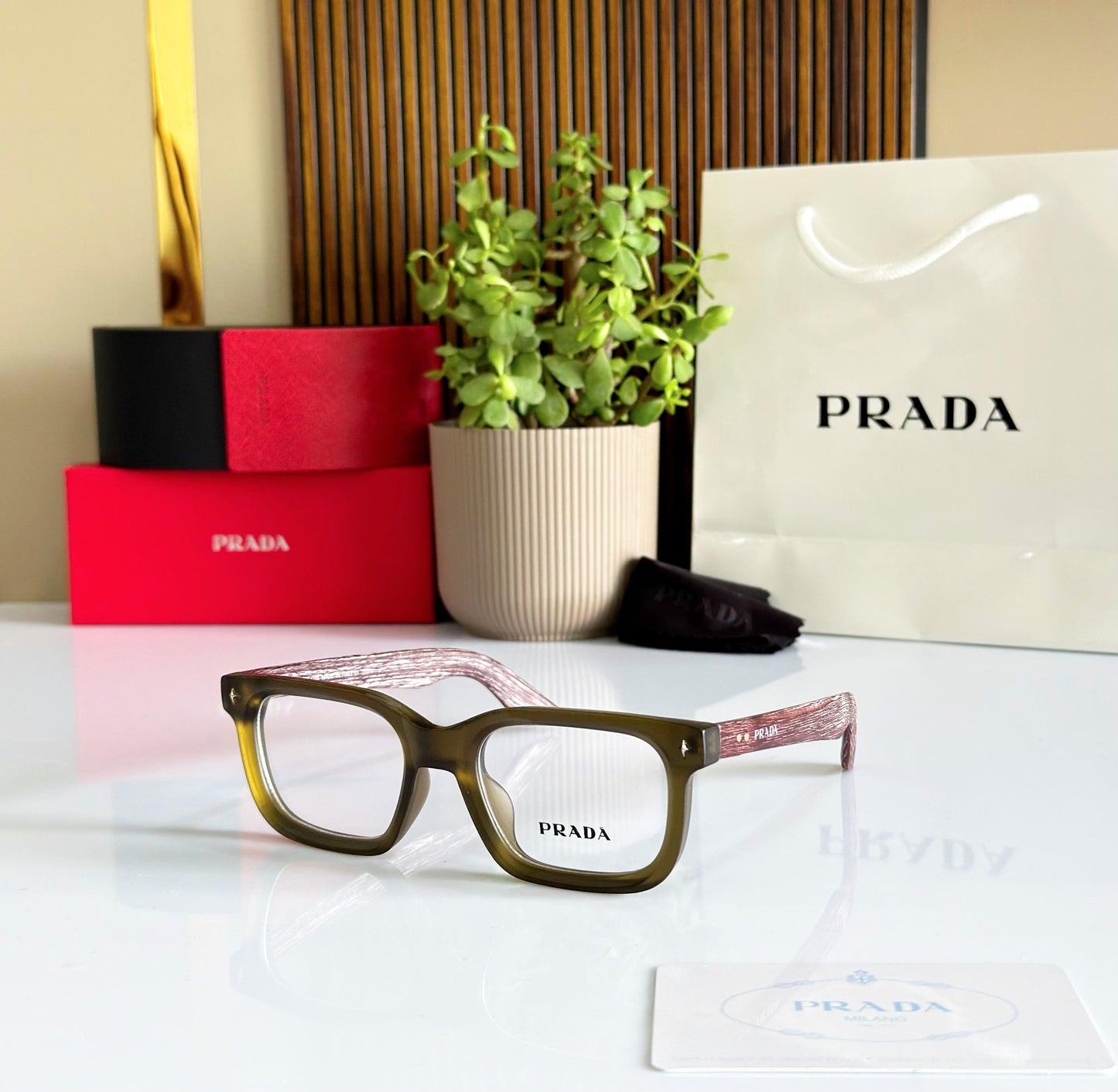 Prada eyeglasses with a Prada shopping bag and boxes in the background