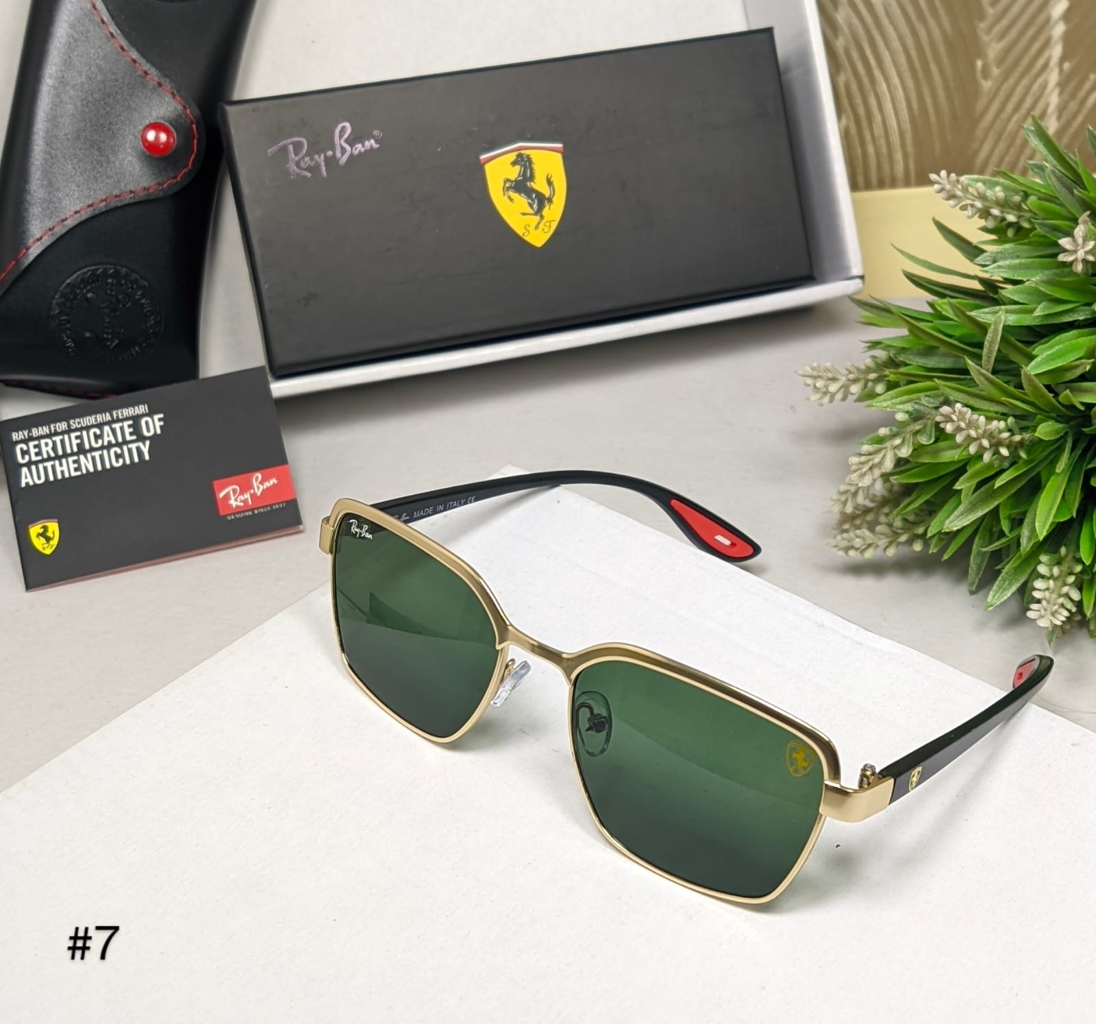 Gold-framed sunglasses with green lenses on a white surface, accompanied by a Ray-Ban box and certificate of authenticity.