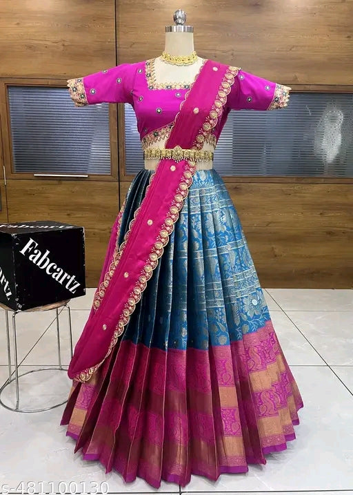 Traditional outfit with pink blouse and blue saree on a mannequin against a wooden wall.