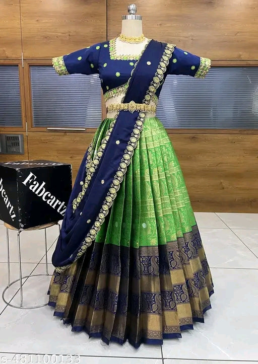 Green and blue saree with gold border on a mannequin against a wooden panel background.