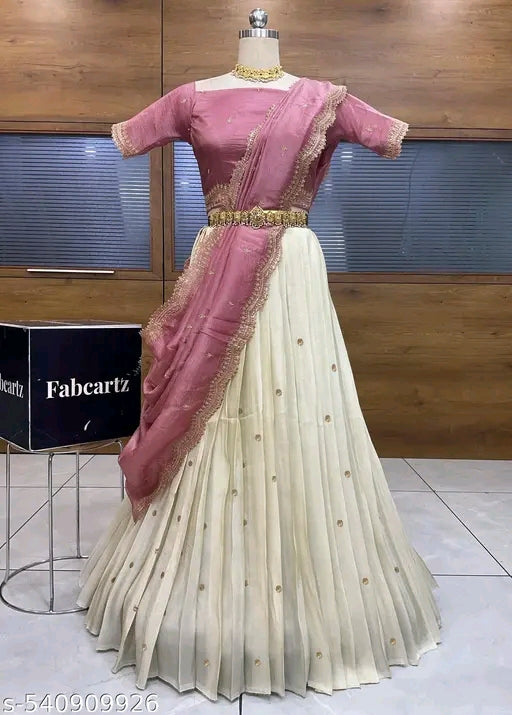 Saree with pink blouse and white skirt on a mannequin against a wooden panel background.